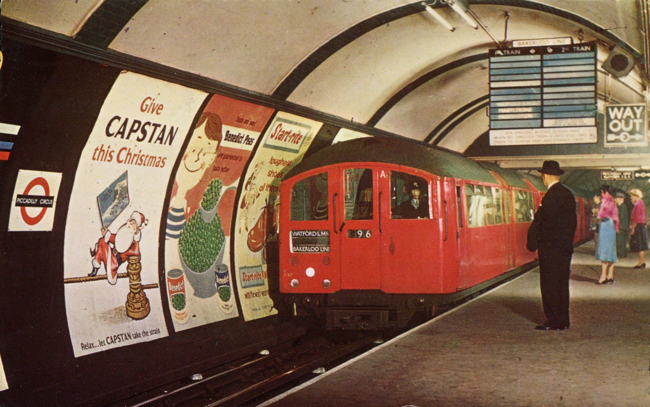 a red tube train comes along the platform underground, old photo probably from around the 1970s.